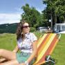 Woman relaxing on a deck chair at the campsite by the lake.