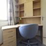 A modern desk with a gray office chair and a shelf with drawers and compartments.