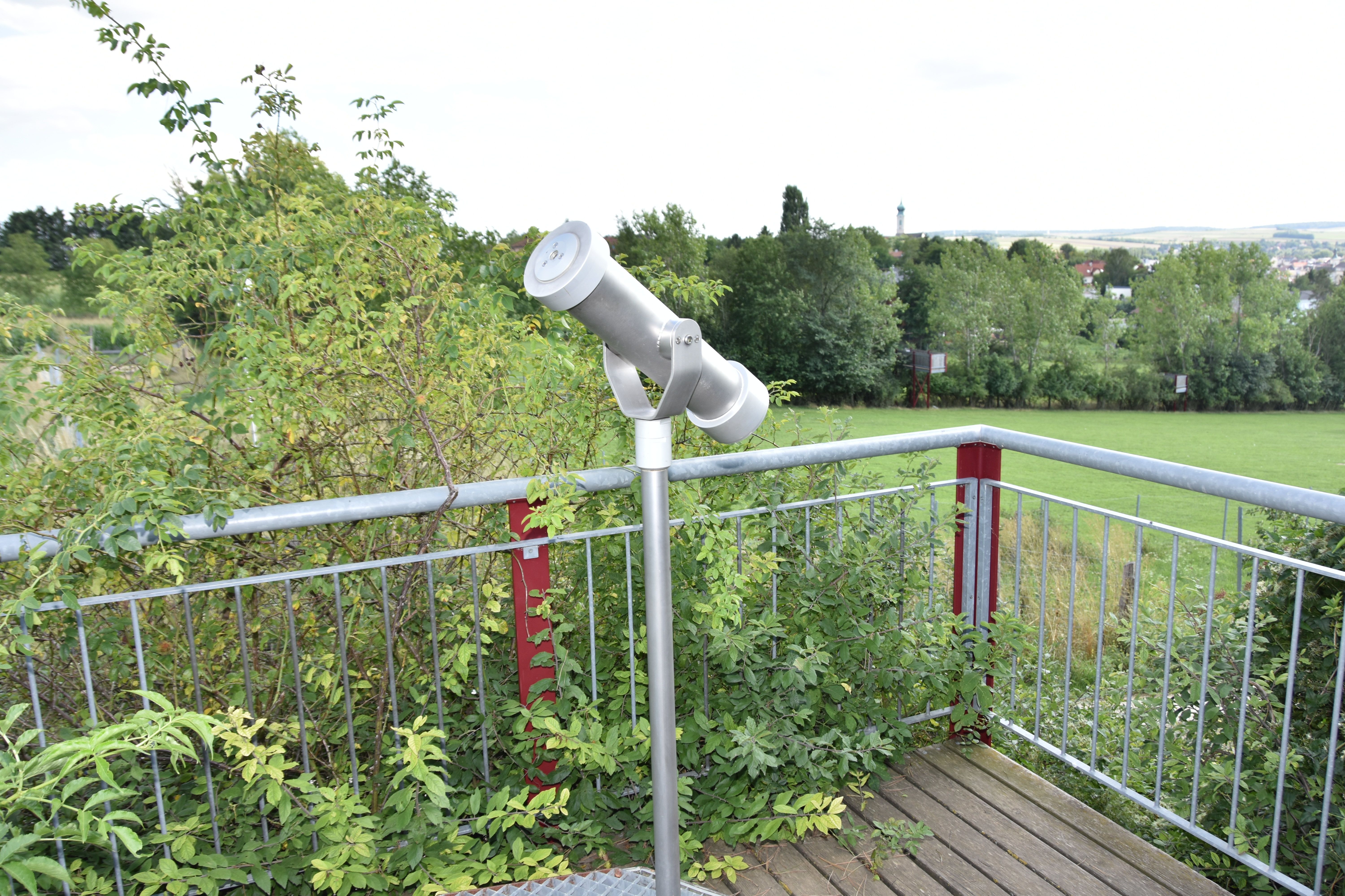 Viewing platform with telescope and view of the green landscape.