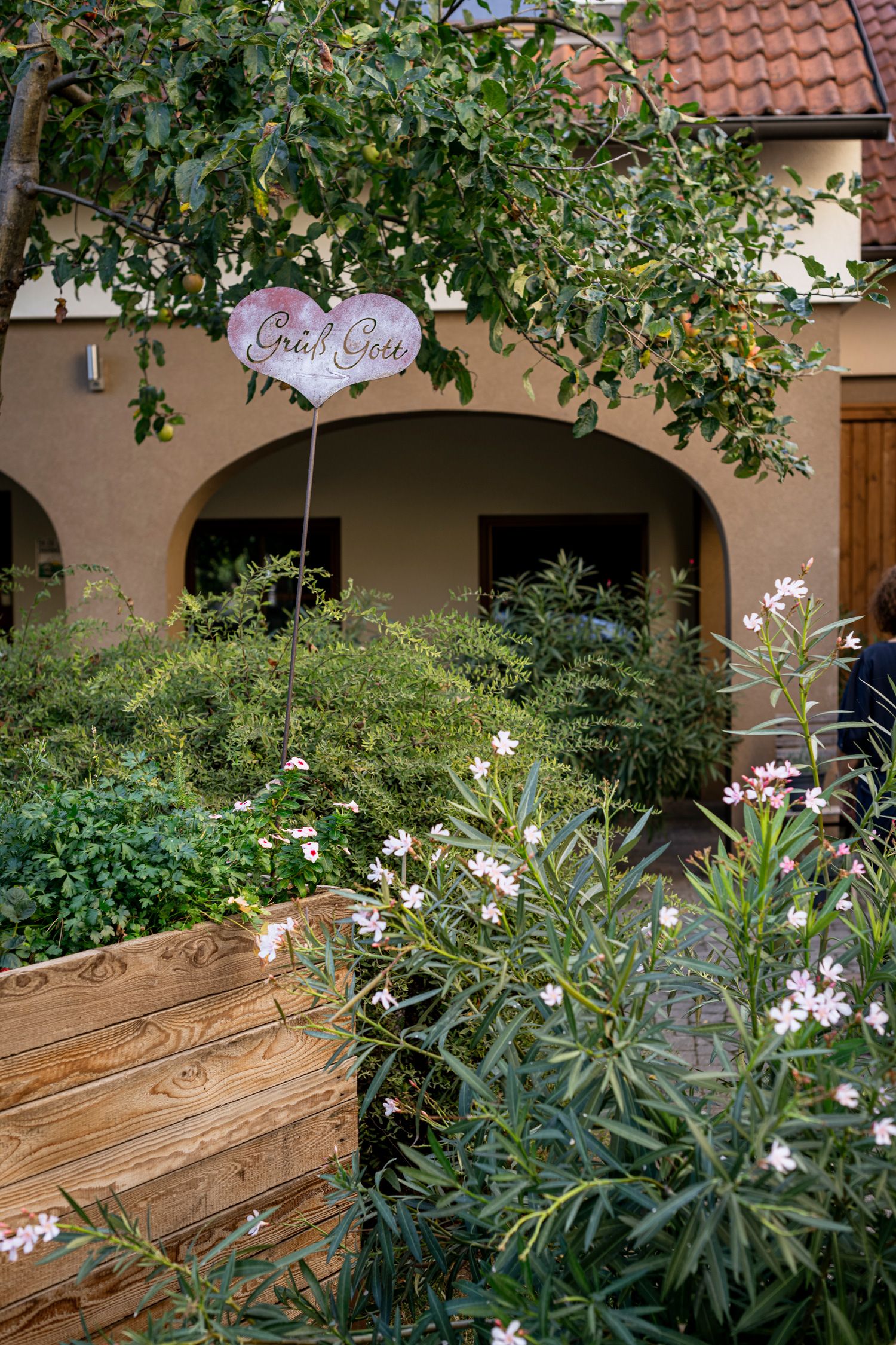An inner courtyard with plants, a wooden bed and a sign saying 'Grüß Gott'.