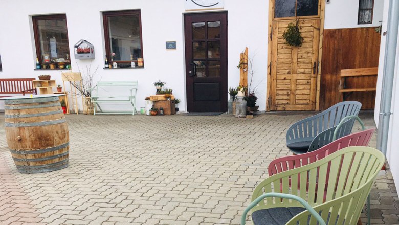 Seating area in front of a department store with colorful chairs and a barrel.
