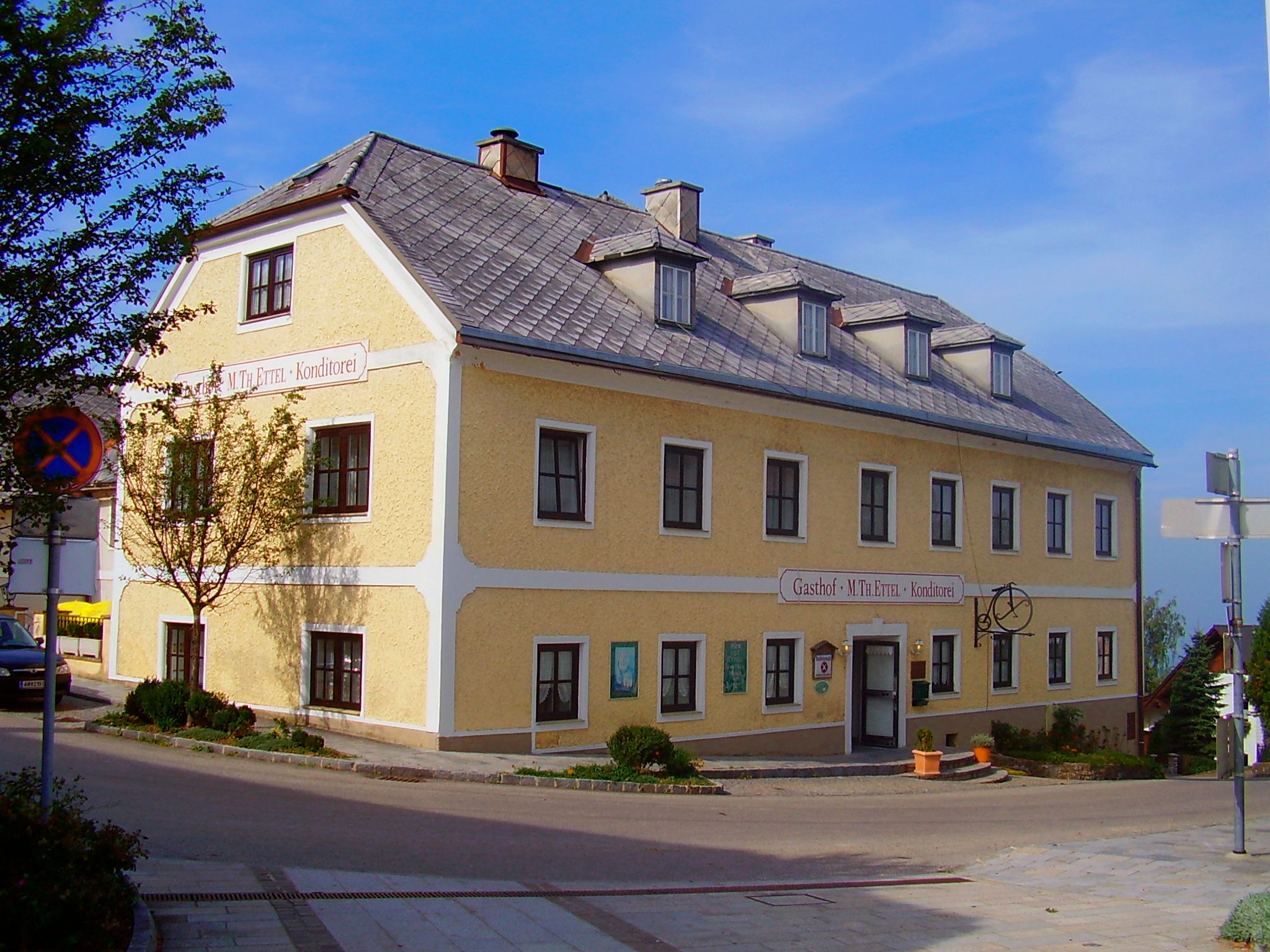 Yellow two-storey building with the inscription 'Gasthof M. Th. Ettel Konditorei'.