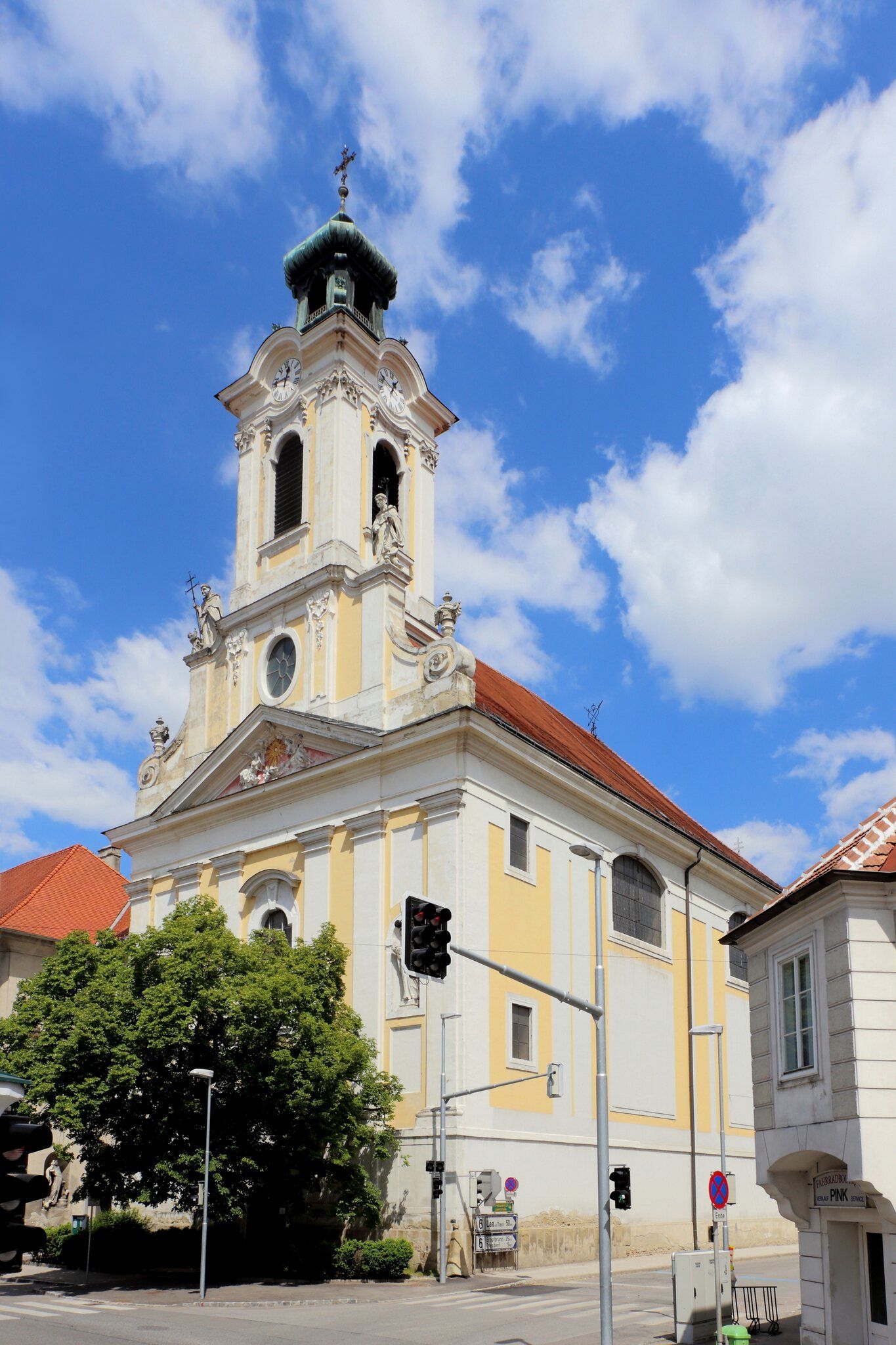 Baroque church with tower and clock against a blue sky.