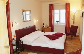 Cozy bedroom with red bed and decor.