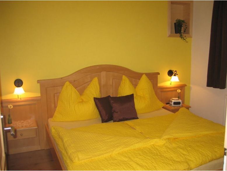 Cozy guest room with yellow bedding and wooden furniture.