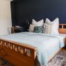 Cozy bedroom with wooden bed, blue wall and decorative pillows.