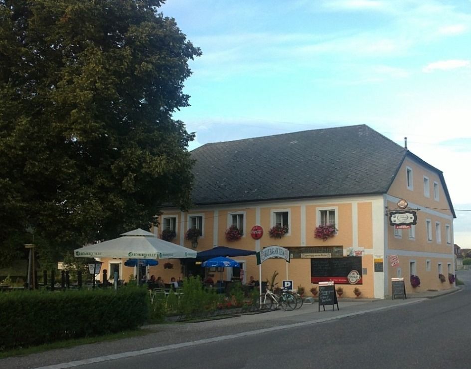 Front view of a traditional pub with beer garden and parasols.