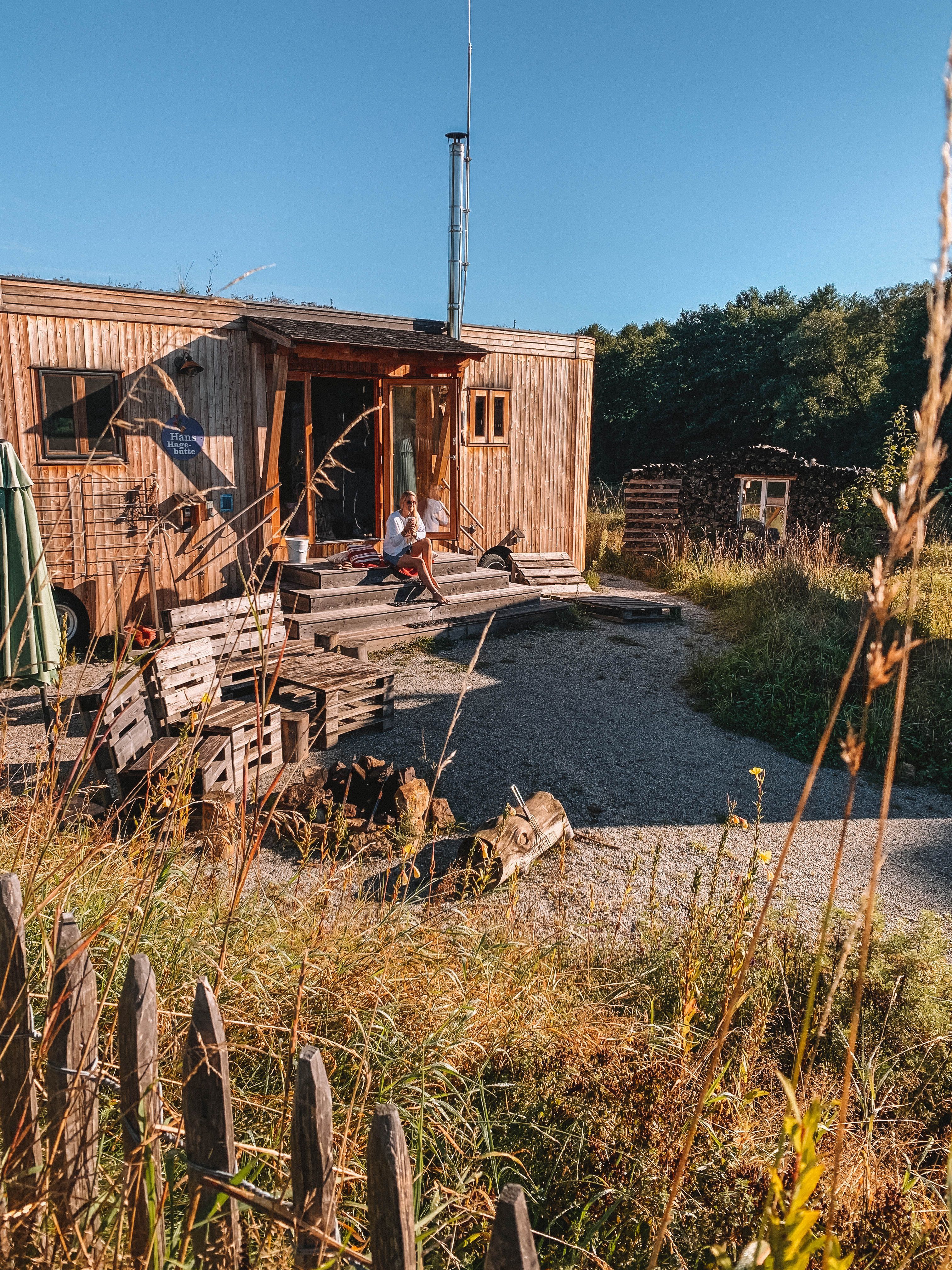 Two rustic wooden houses with green roofs in a rural setting.