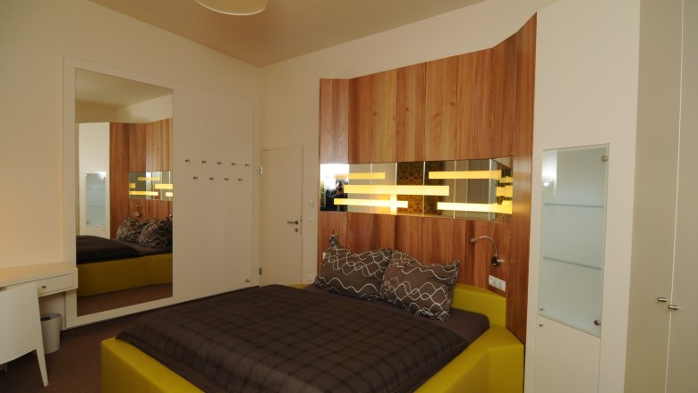Modern bedroom with wood paneling and yellow bed.
