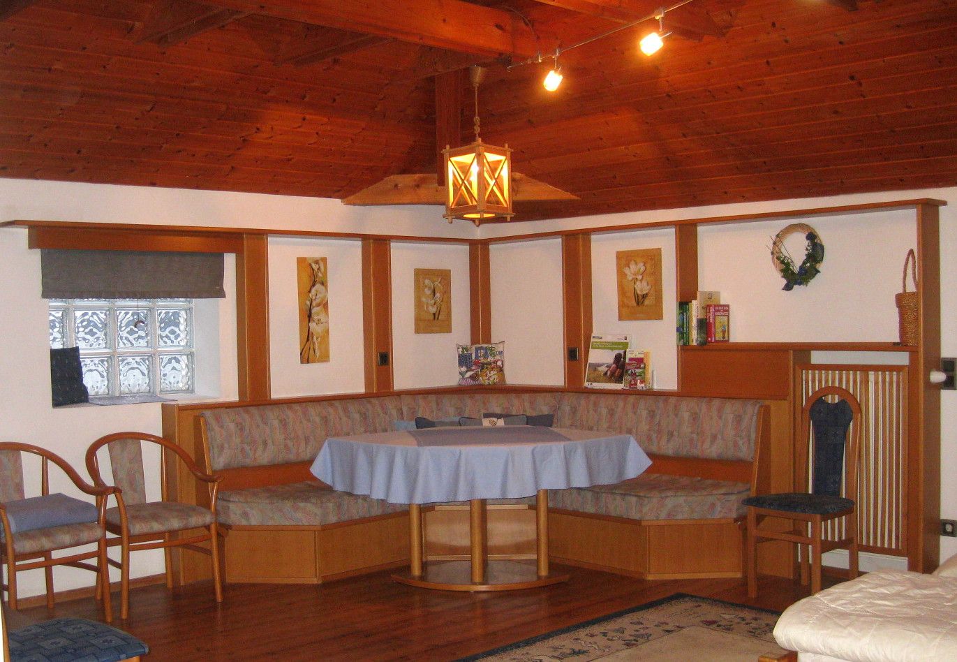 Cozy sitting area with wooden furniture and blue tablecloth in a room with a wooden ceiling.