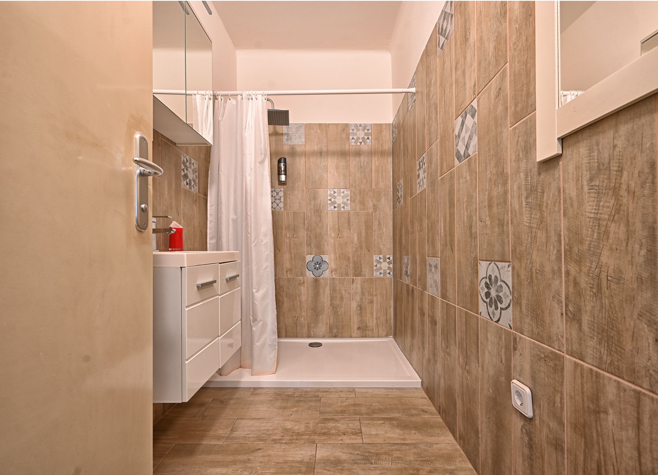 Modern bathroom with shower cubicle, tiled walls and washbasin.