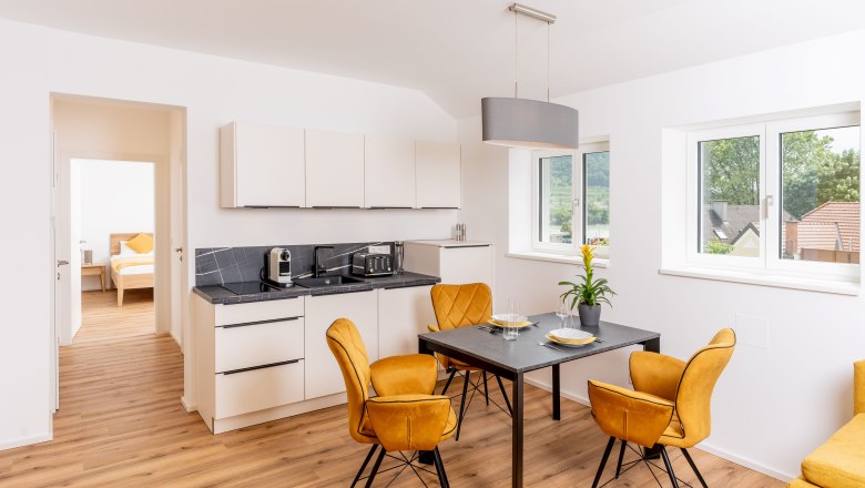 Modern kitchen with dining table and yellow chairs in a vacation apartment.