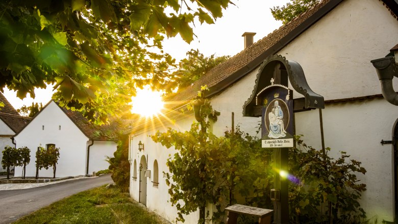 Sunset in the Sitzendorf wine cellar lane with old wine cellars and a religious wayside shrine.