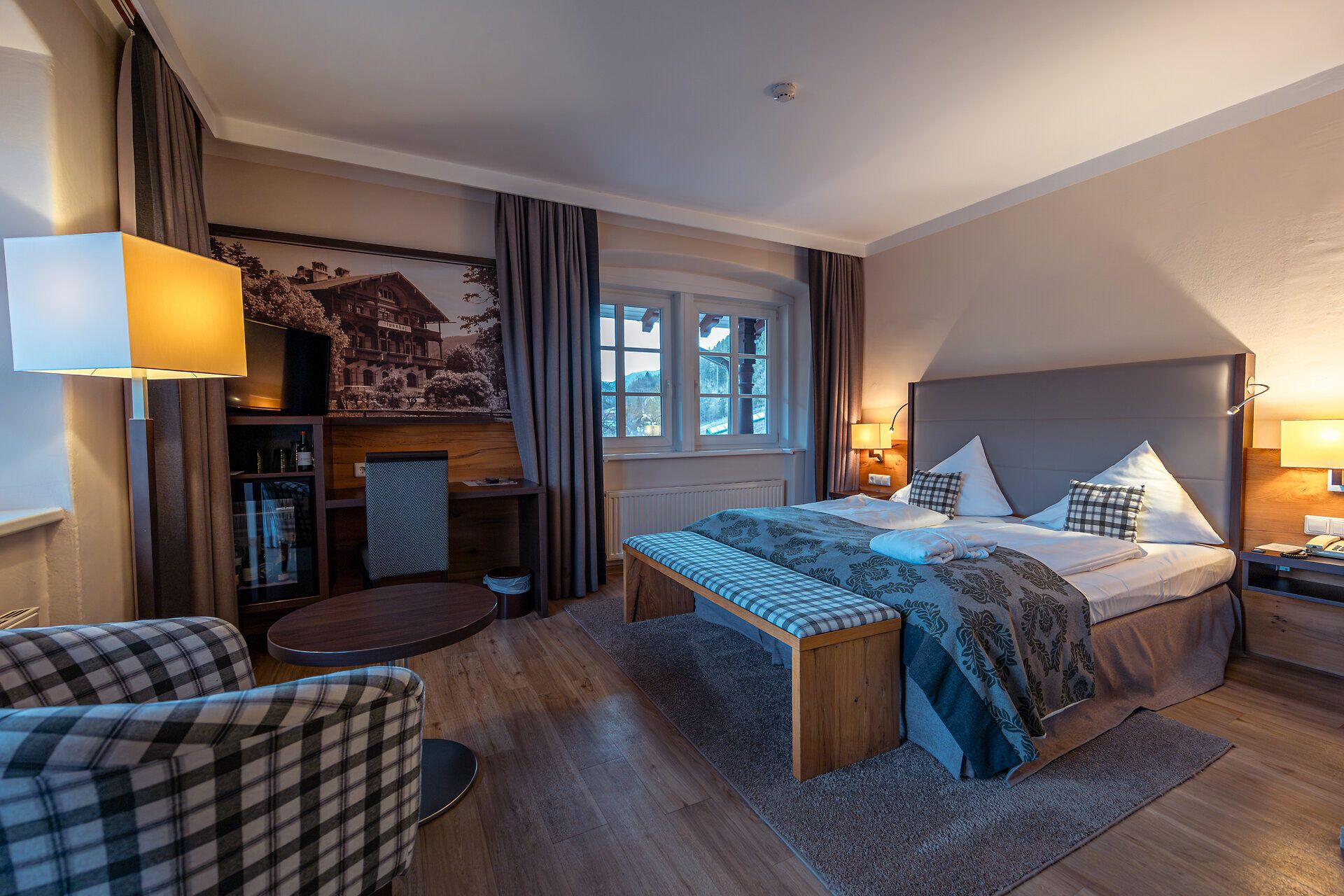 Hotel room with double bed, armchair, table and window with a view.