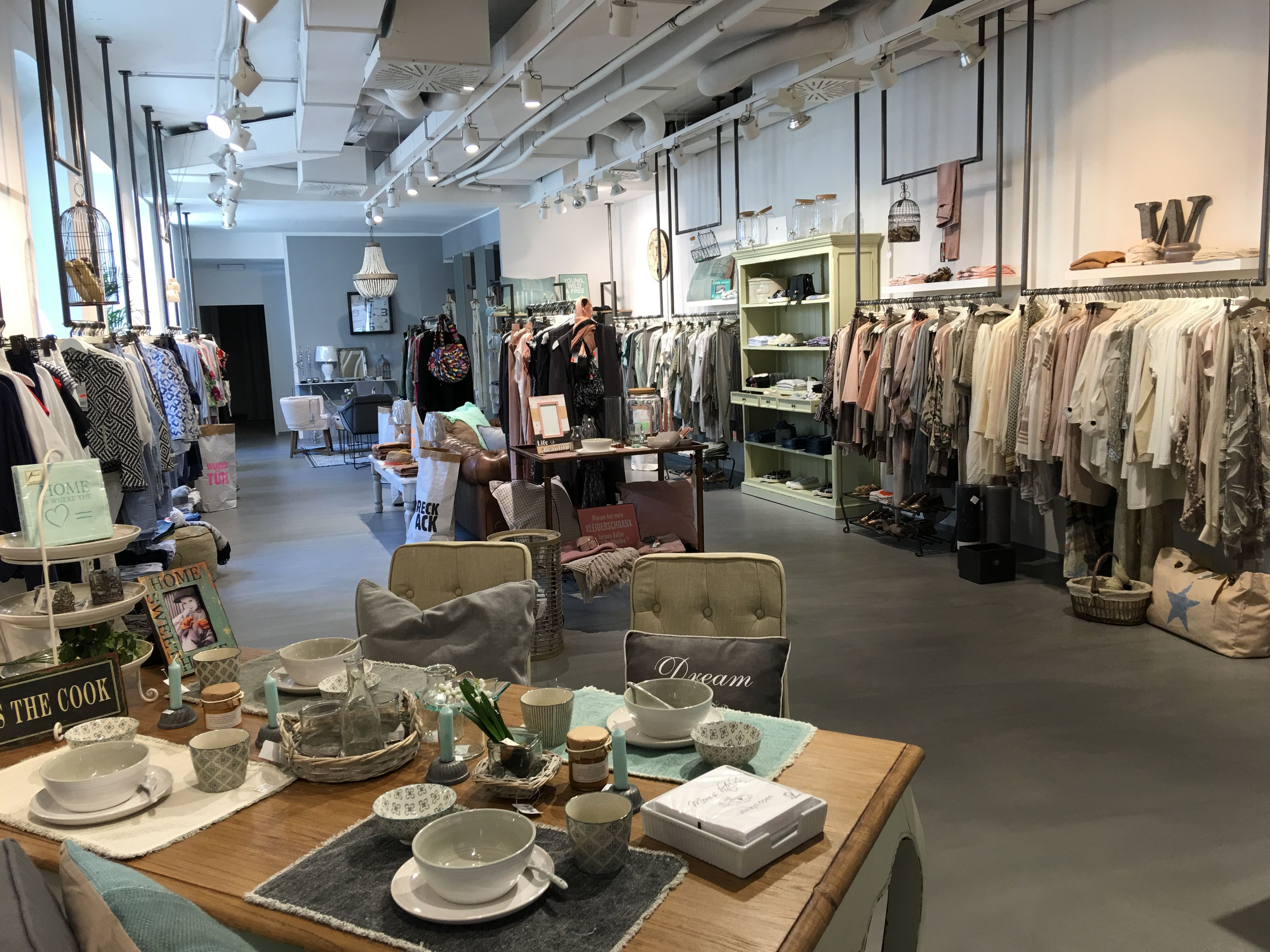 Interior view of a stylish clothing store with clothing and decorative items.