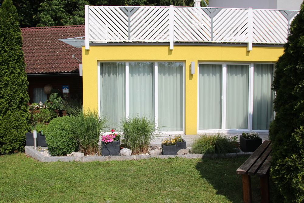 Yellow garden apartment with large windows and well-kept garden.