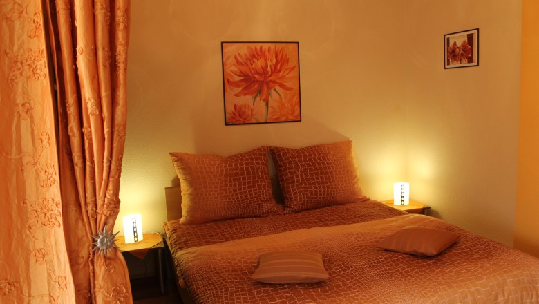 A cozy bedroom with orange decoration and lighting.