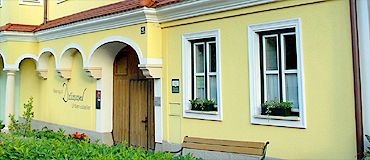 Yellow building with white window frames and wooden door.