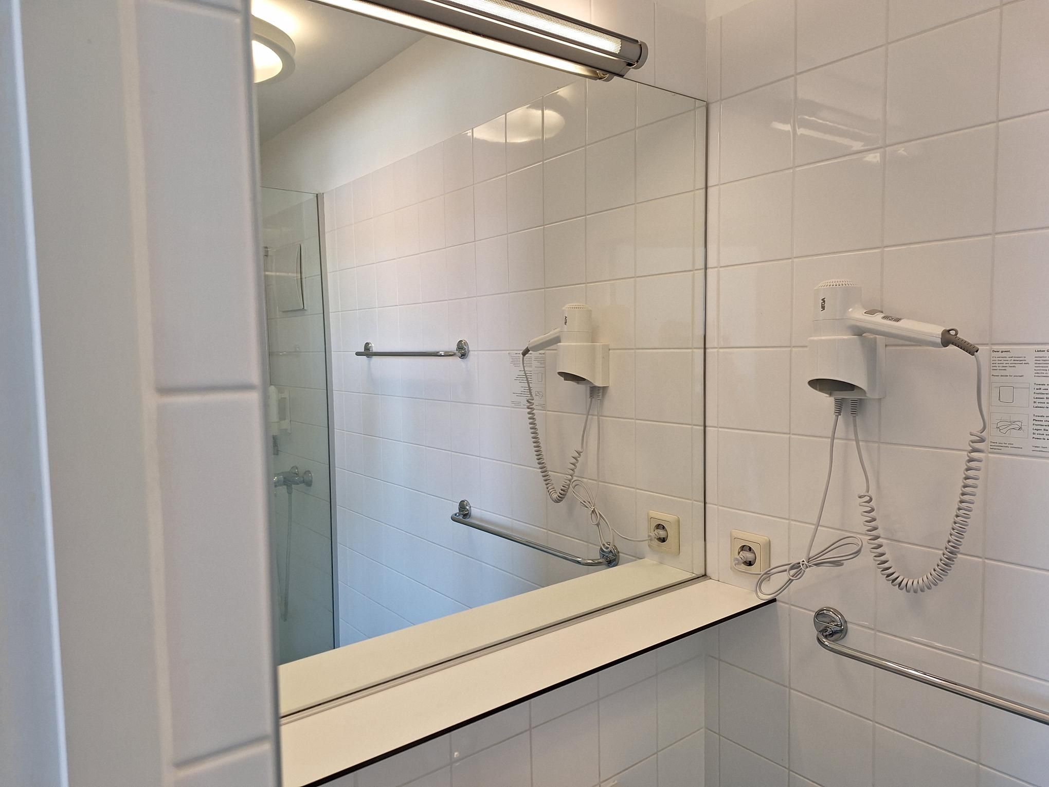 Modern bathroom with mirror, hairdryer and towel rail.