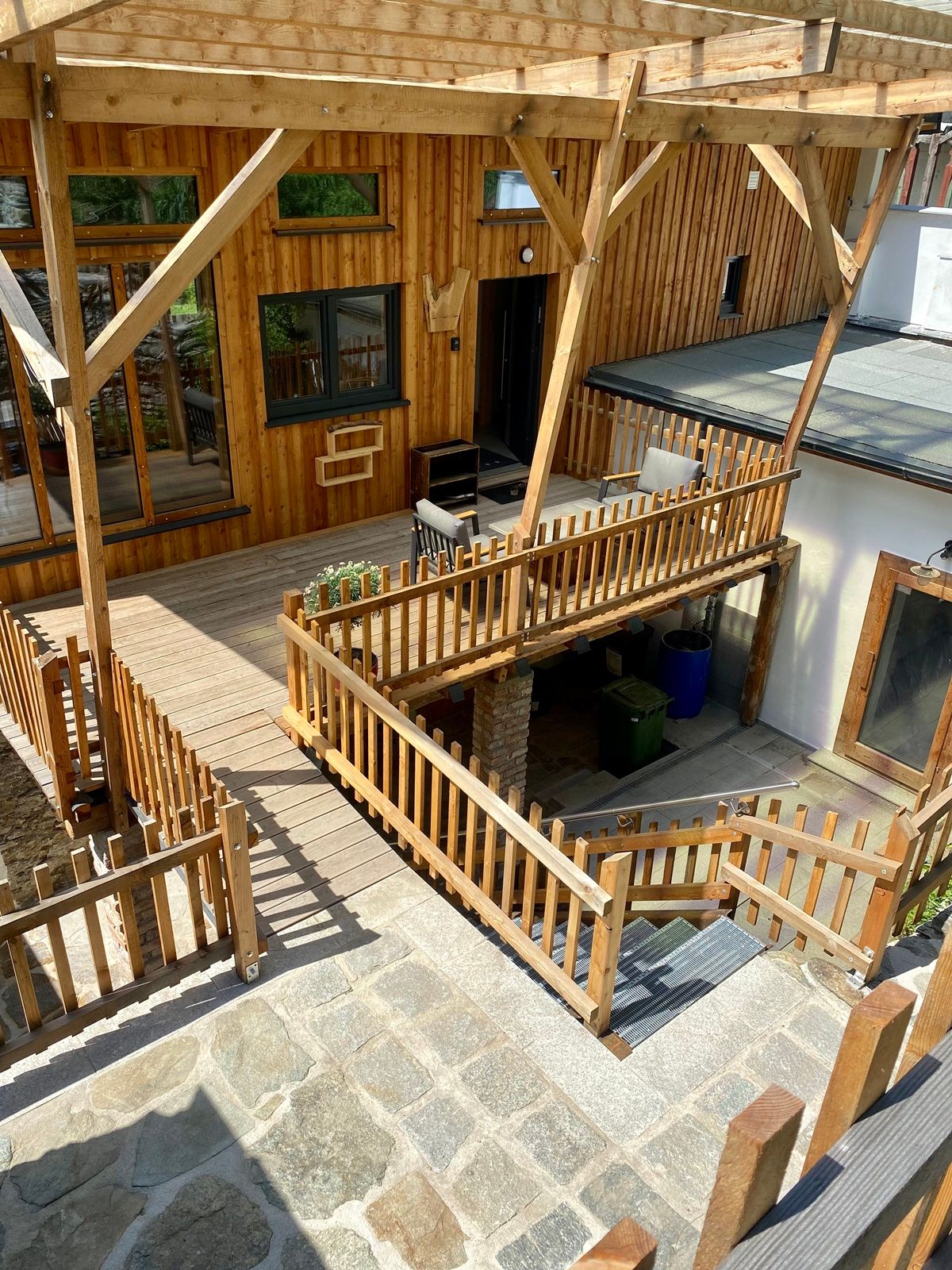 Wooden terrace with railings and adjoining garden area.