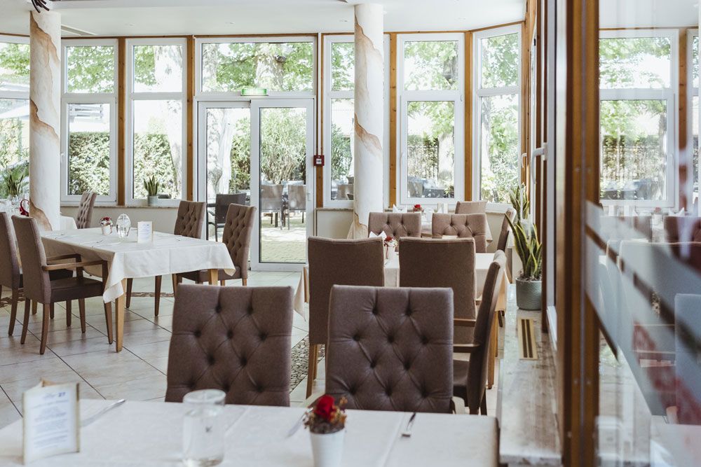 Interior view of an elegant restaurant with set tables and large windows.