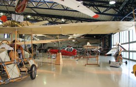 Interior view of an aviation museum with historic airplanes and gliders.