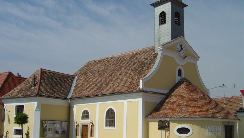 Yellow church with clock tower and 'Weinkirche' lettering.