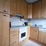 Kitchen with wooden cupboards, stove, sink and worktop.