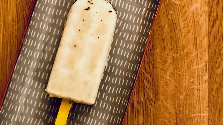 A popsicle on a patterned plate on a wooden table.