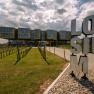 Modern architecture of LOISIUM Langenlois with vines in the foreground and a cloudy sky.