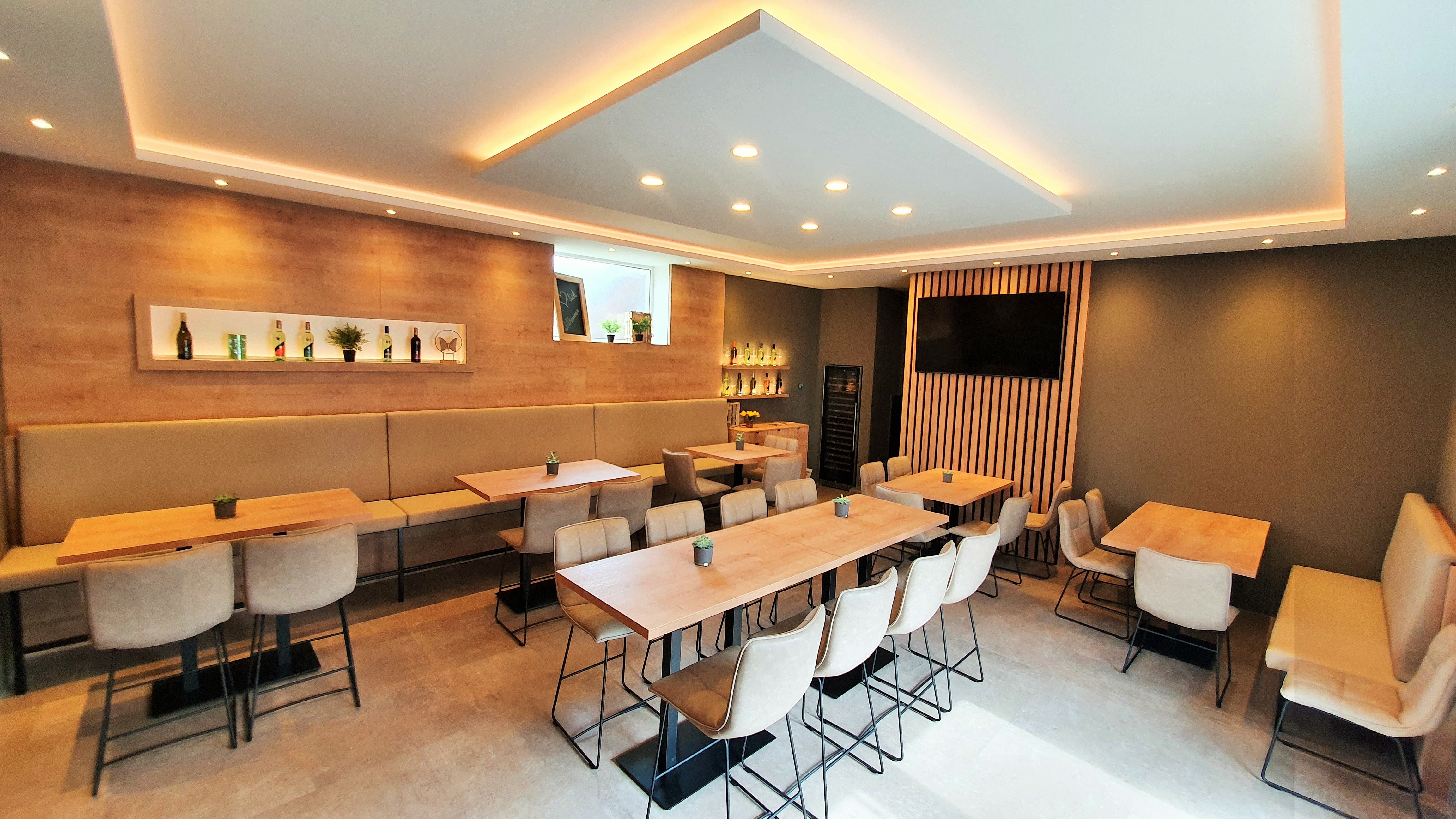 Modern tasting room with wooden tables, upholstered chairs and decorative shelves with bottles.