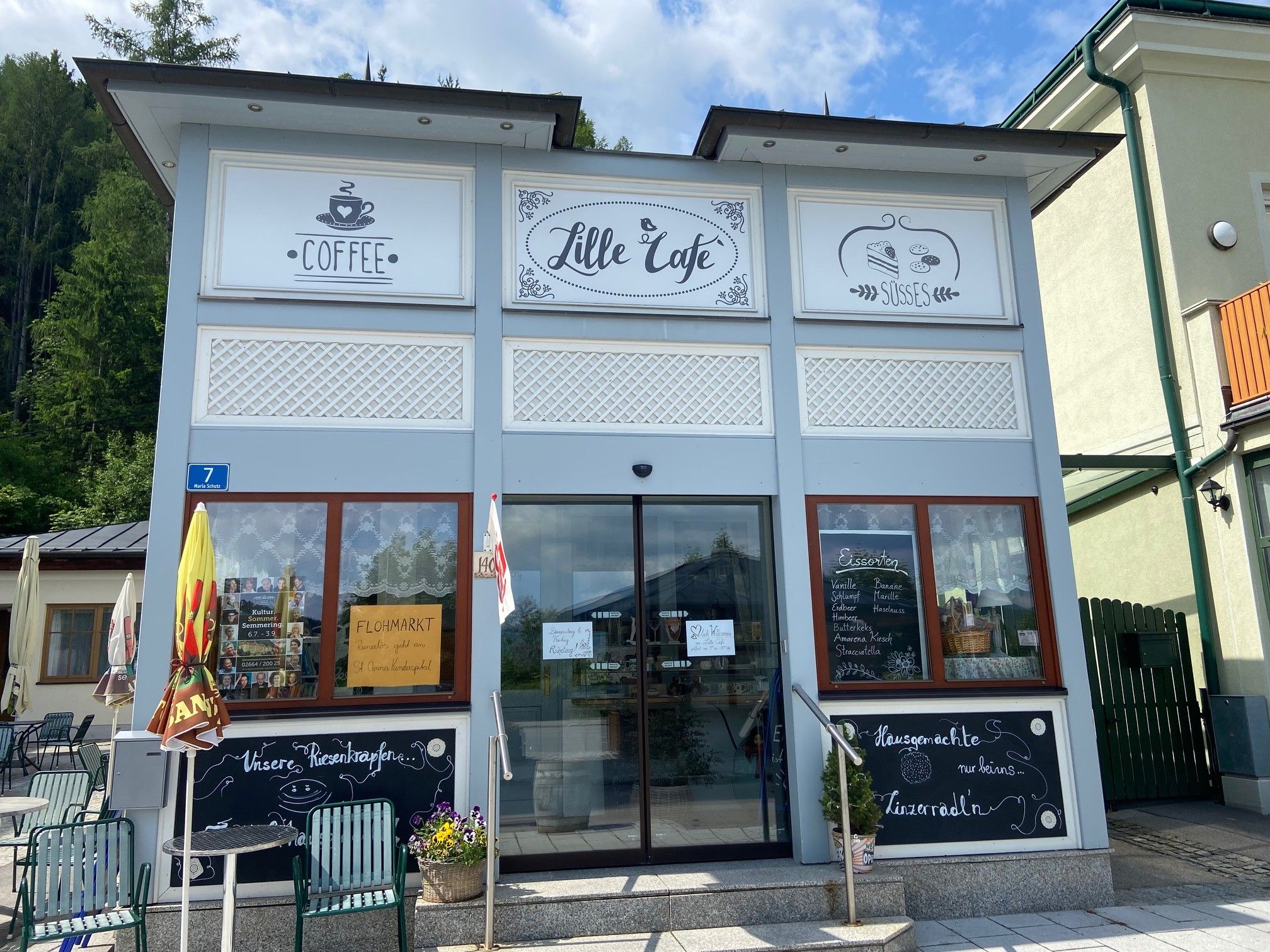 Exterior view of a café with signs for coffee and sweets.