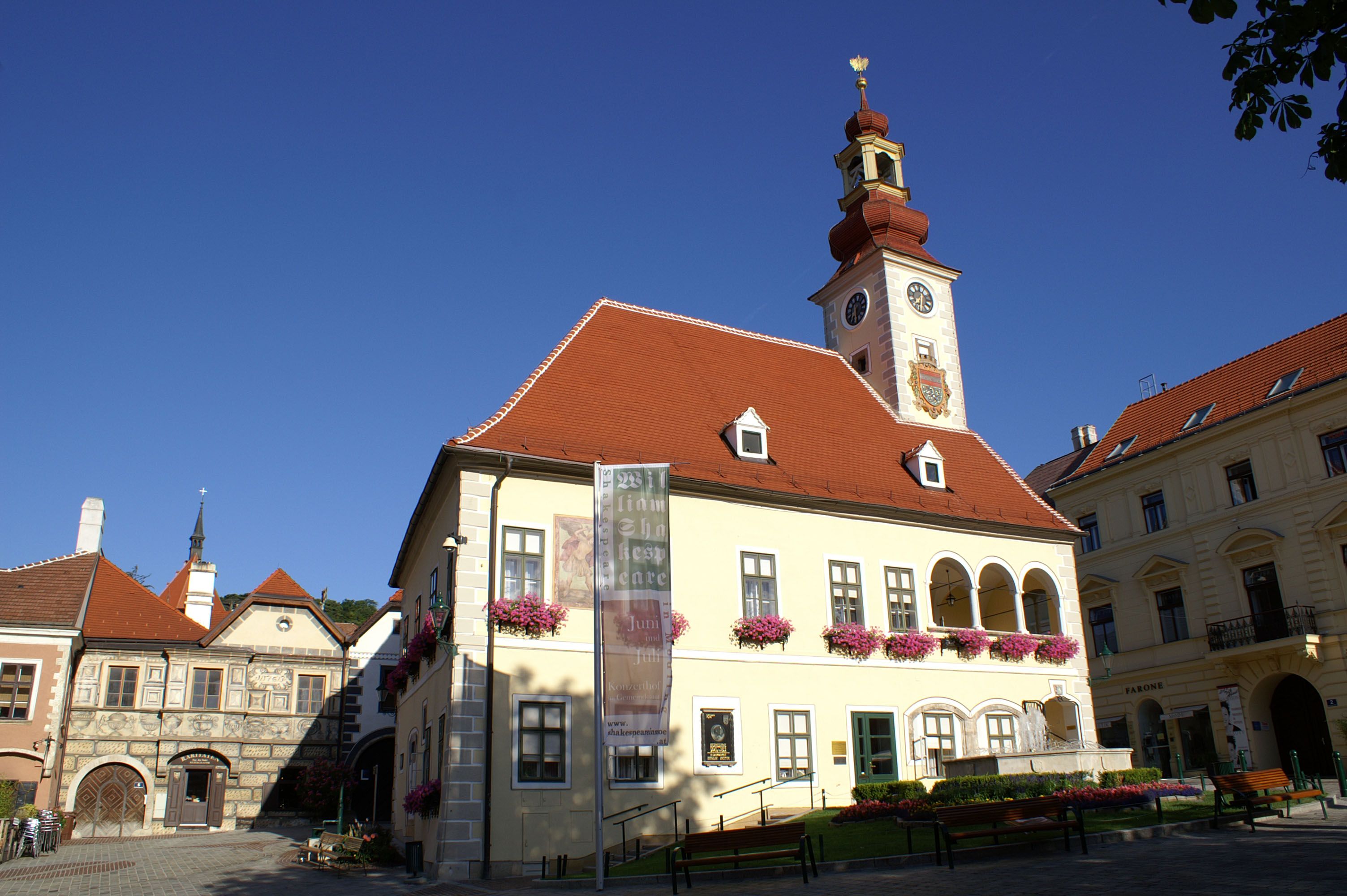 Historic building with tower and clock in Mödling, surrounded by blue sky.
