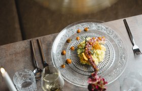 Elegant dish with octopus and garnish served on a glass plate.