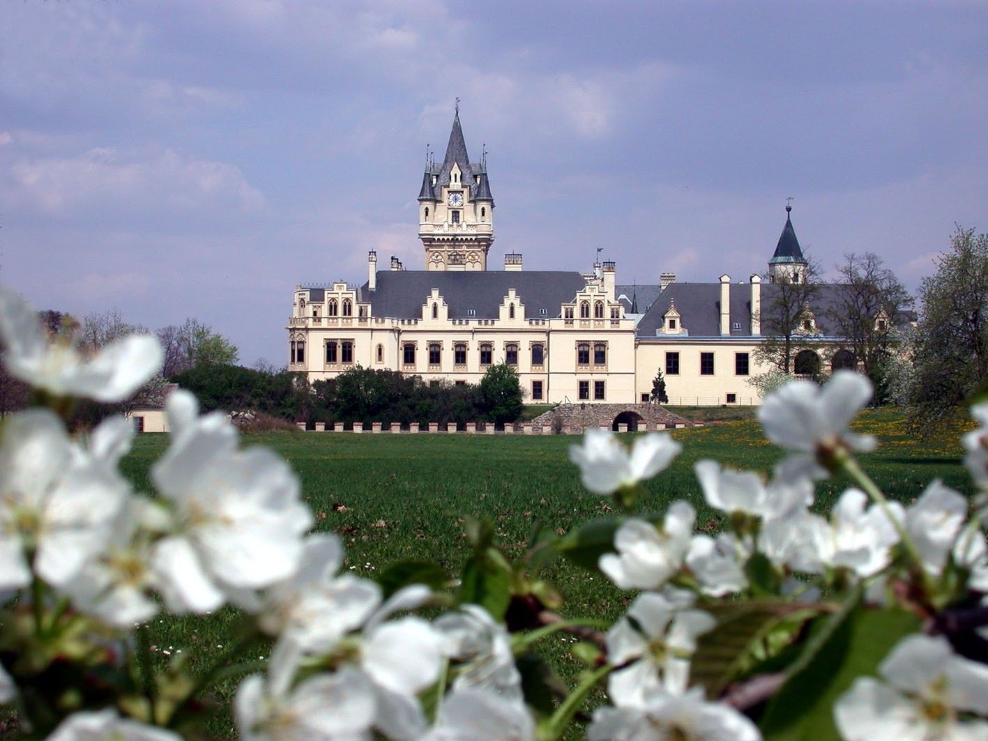 Grafenegg Castle with blossoming trees in the foreground.