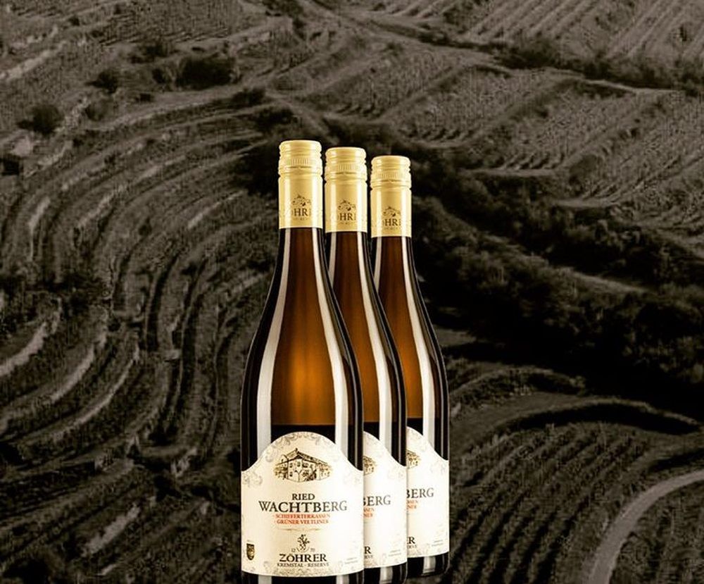 Three bottles of wine against a background of vineyards.