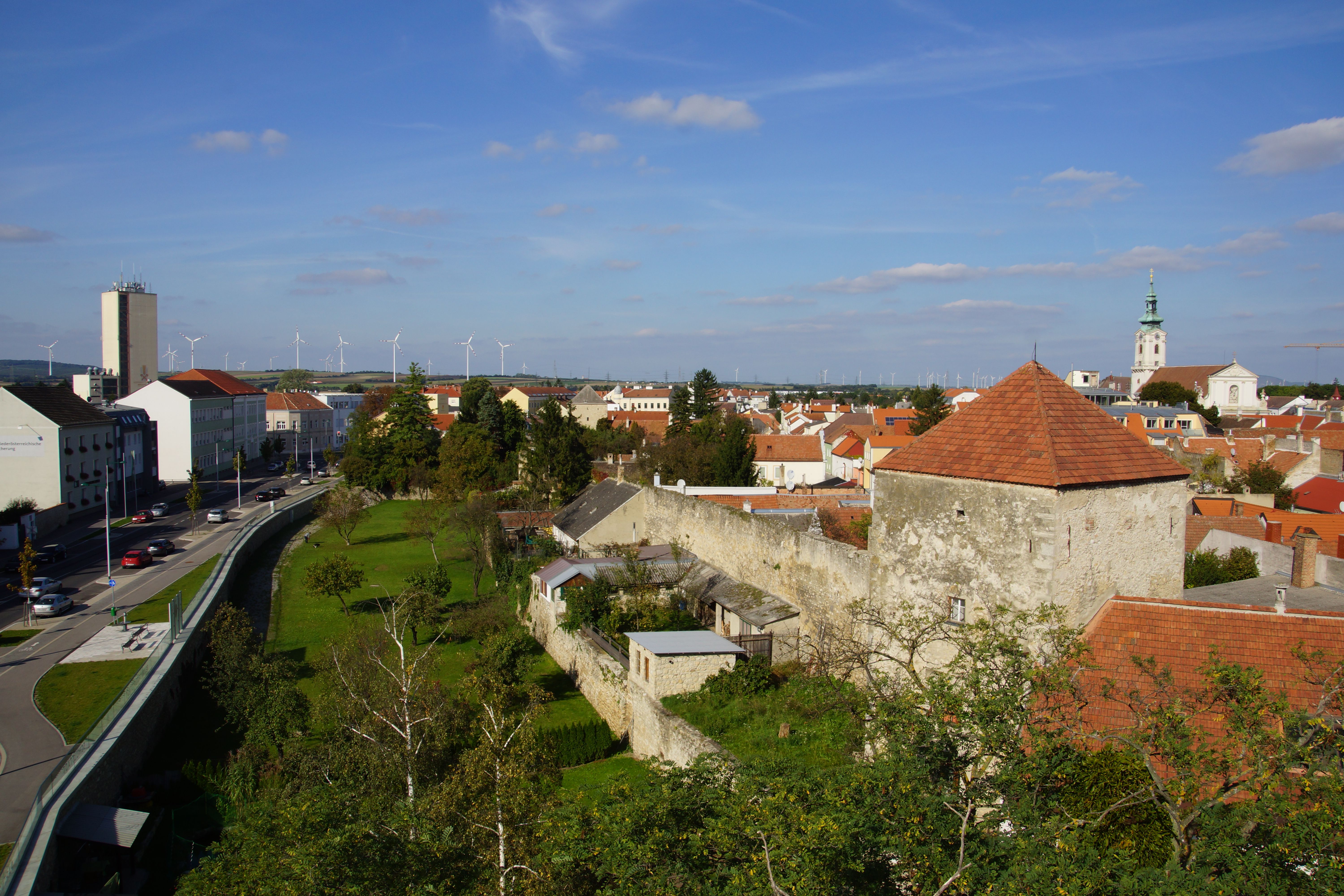 Town view of Bruck an der Leitha with town wall, church and wind turbines in the background.