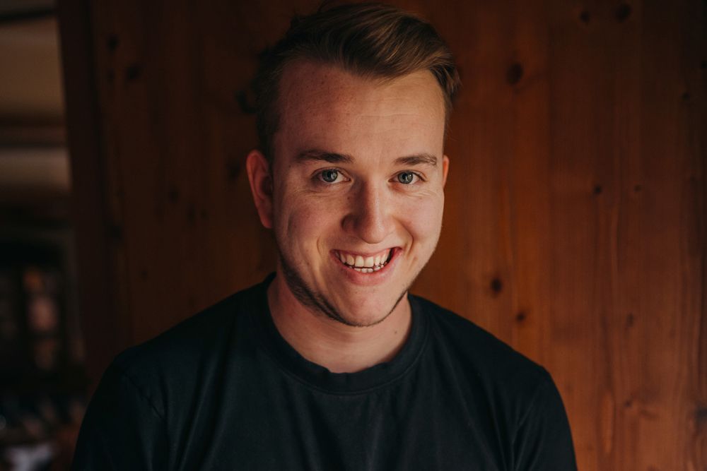 Portrait of a smiling man in front of a wooden wall.