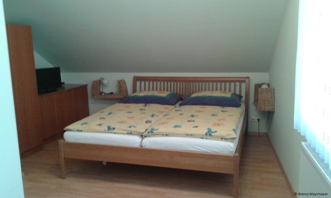 A bedroom with a double bed, a wardrobe and a TV on a cupboard.