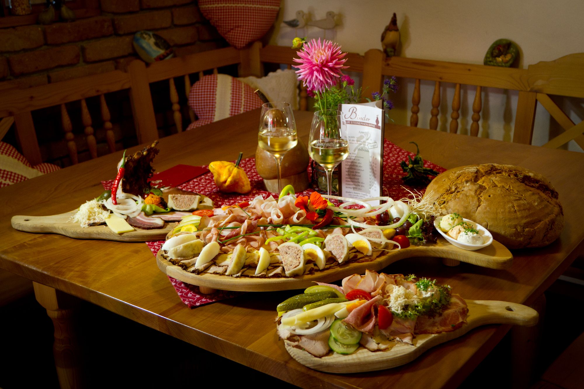 A table with a Heurigen snack: cold cuts, cheese, bread and wine.