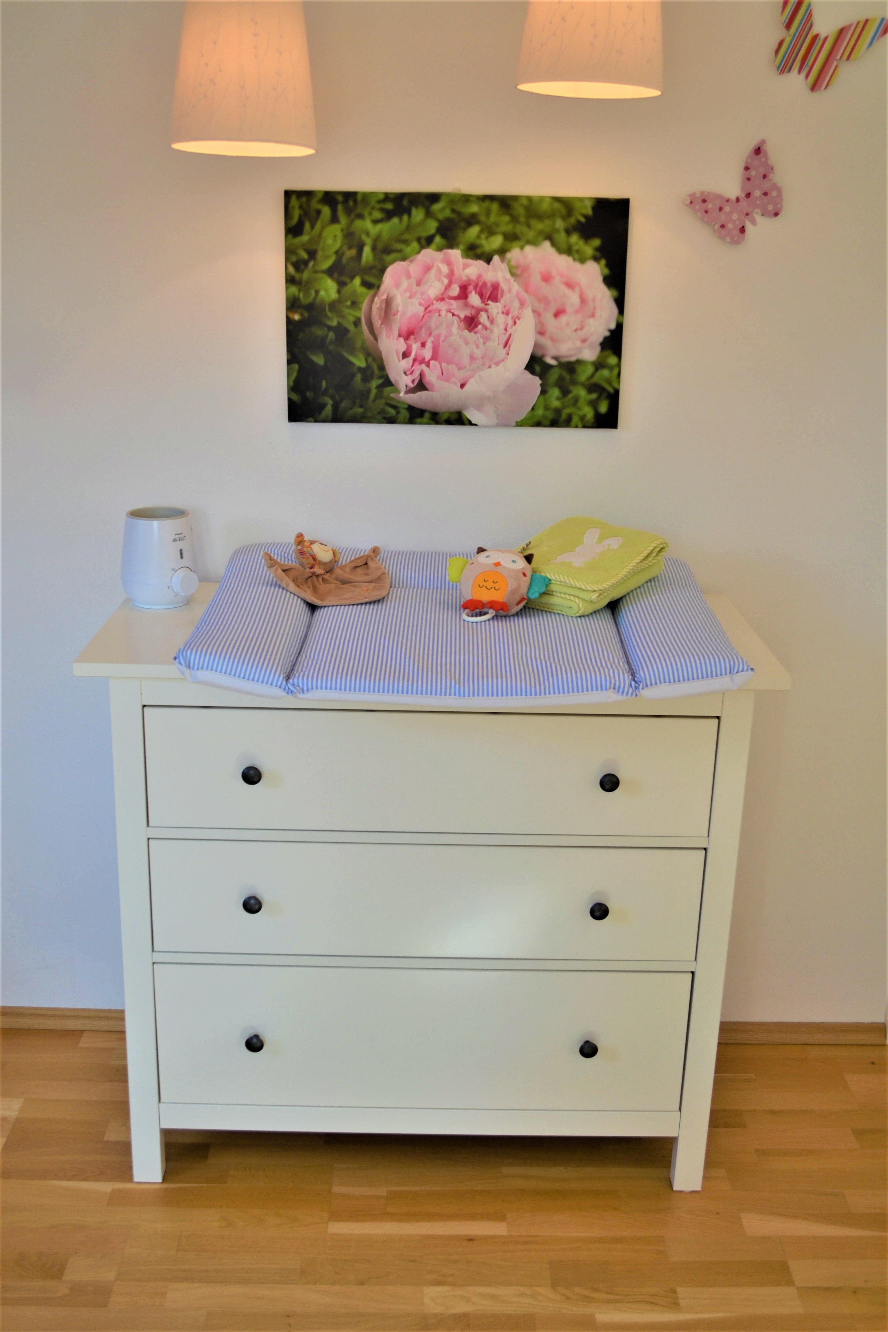 Changing table with blue pad, toys and decorations on the wall.