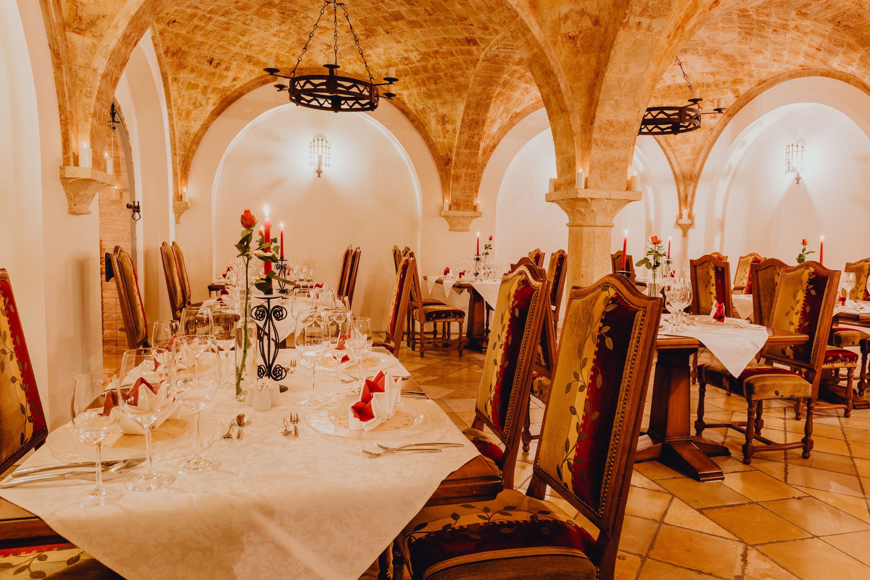 Elegant vaulted cellar with laid tables and candlelight.