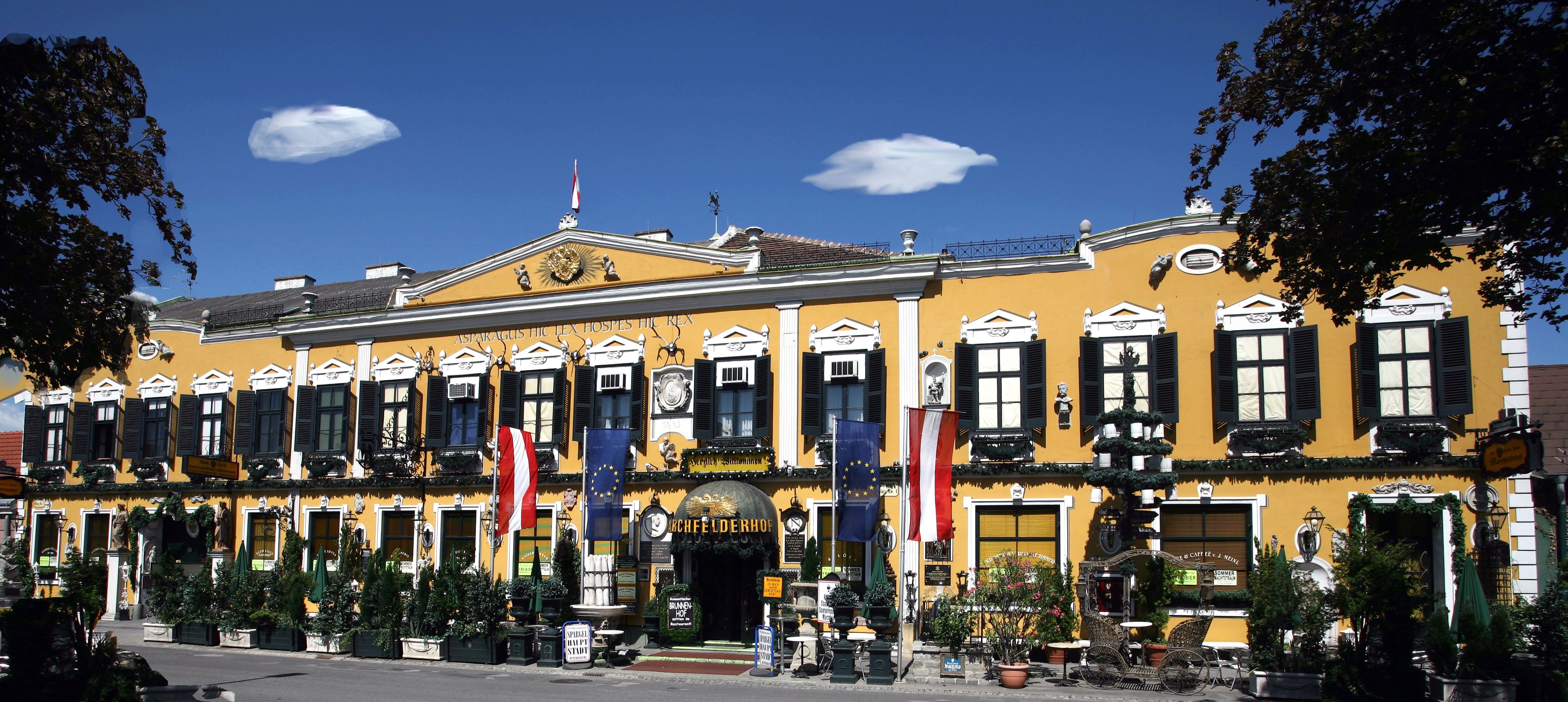 Yellow building with black shutters and Austrian flag.