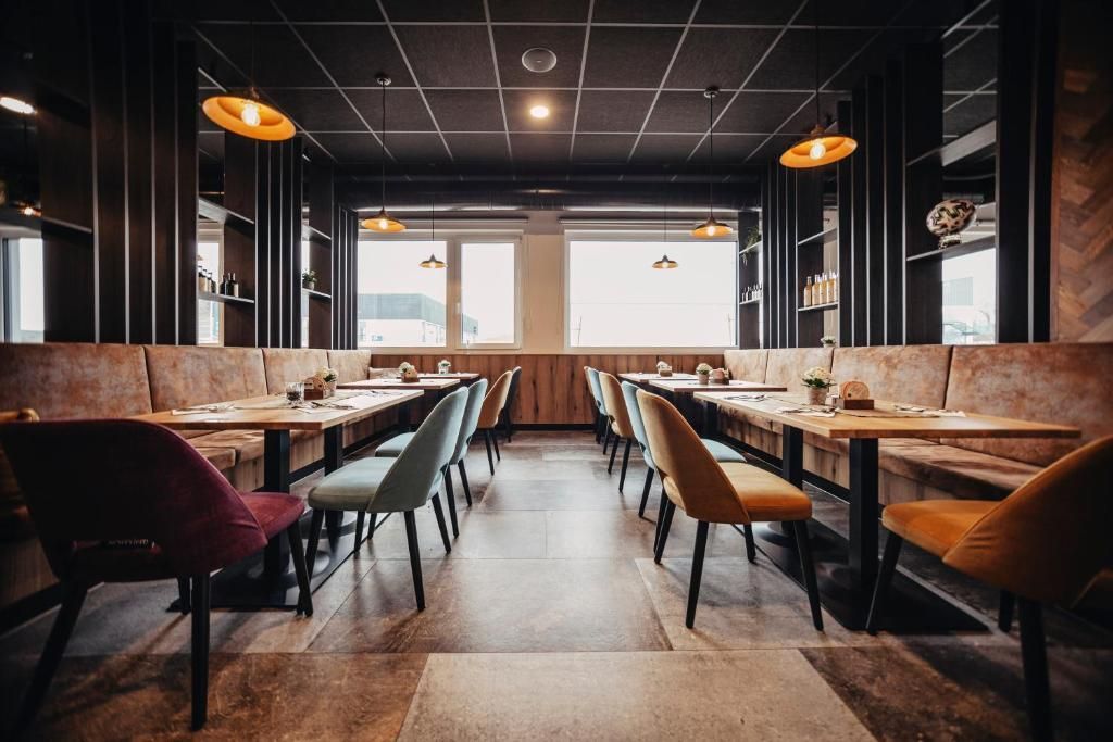 An empty, modern restaurant with tables, upholstered chairs, and warm pendant lights. Title: Egino.