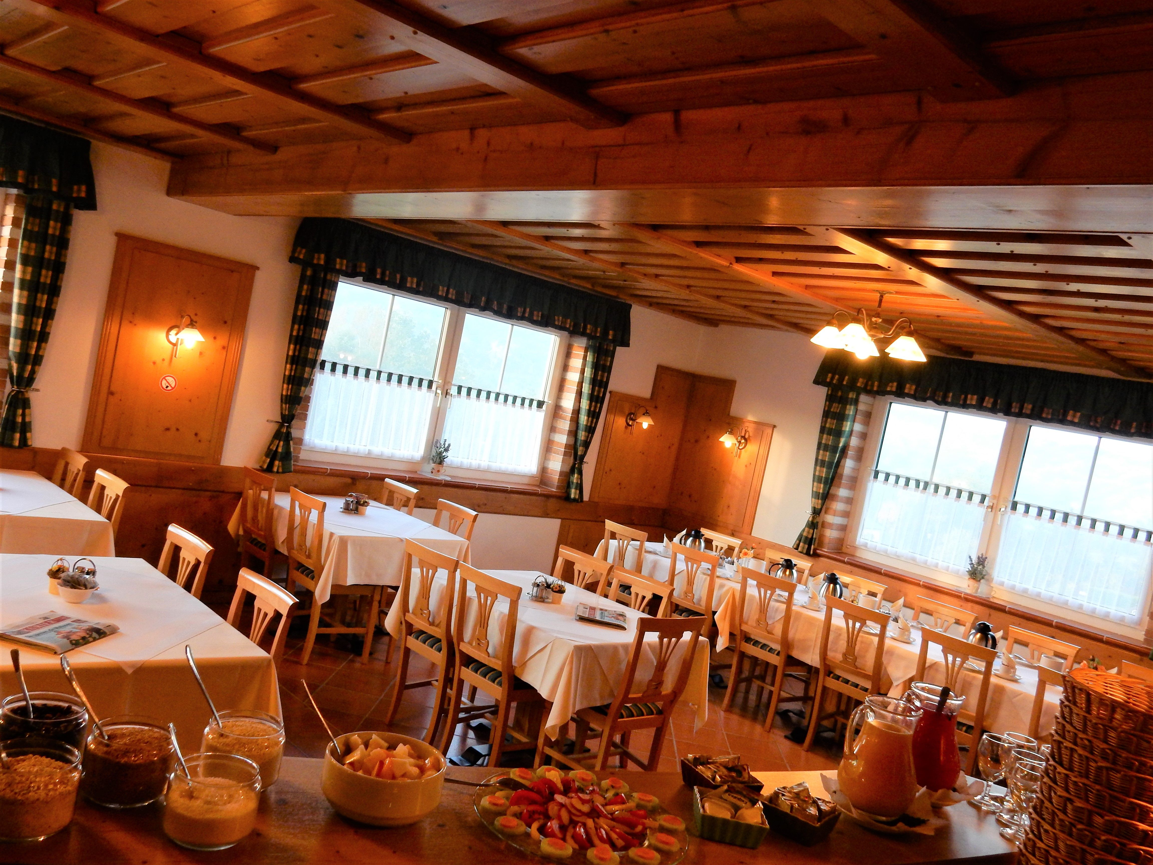 Cozy breakfast room with wooden furniture and laid tables.