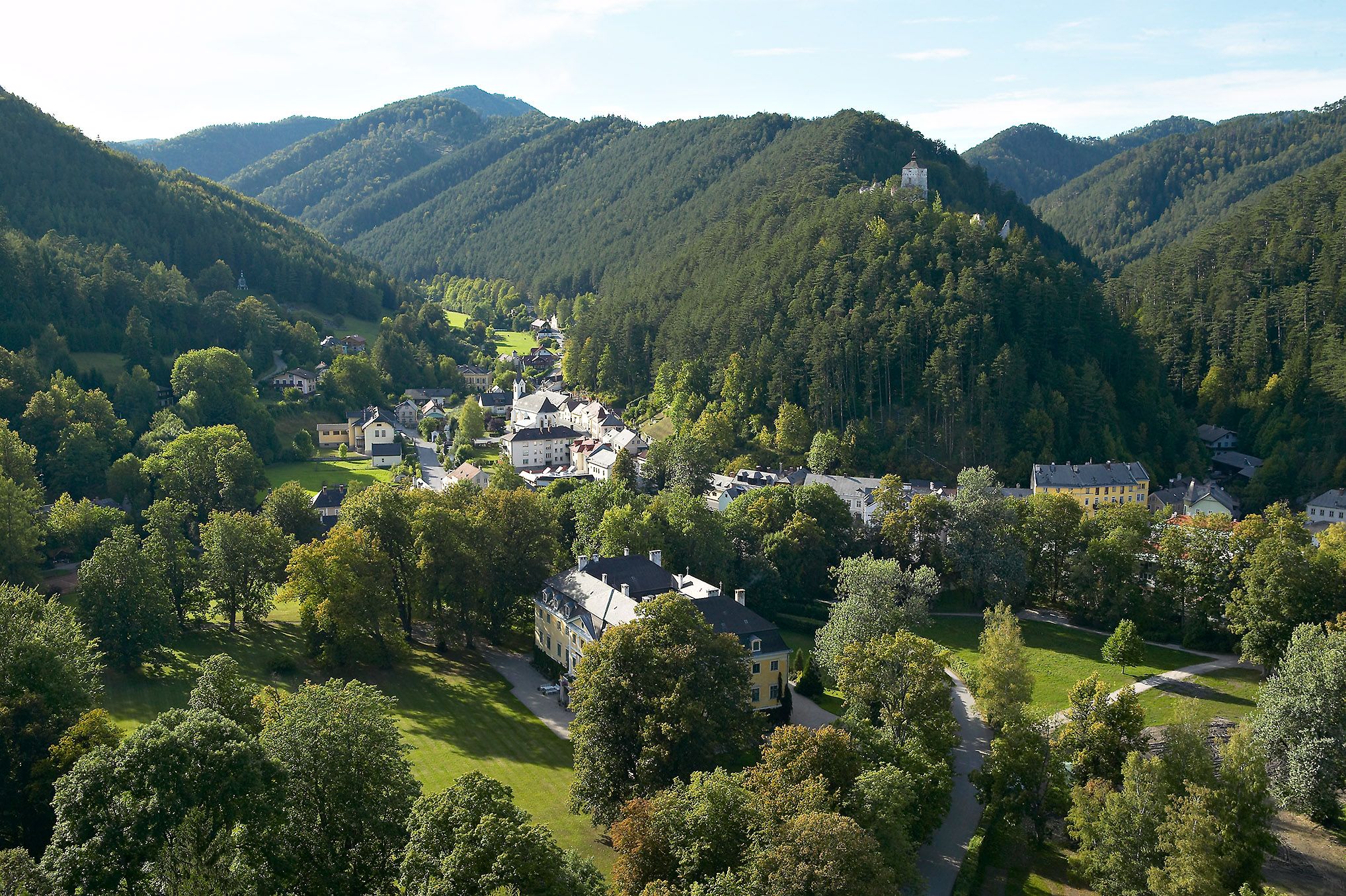 Aerial view of Gutenstein with green hills and a castle on a hill.