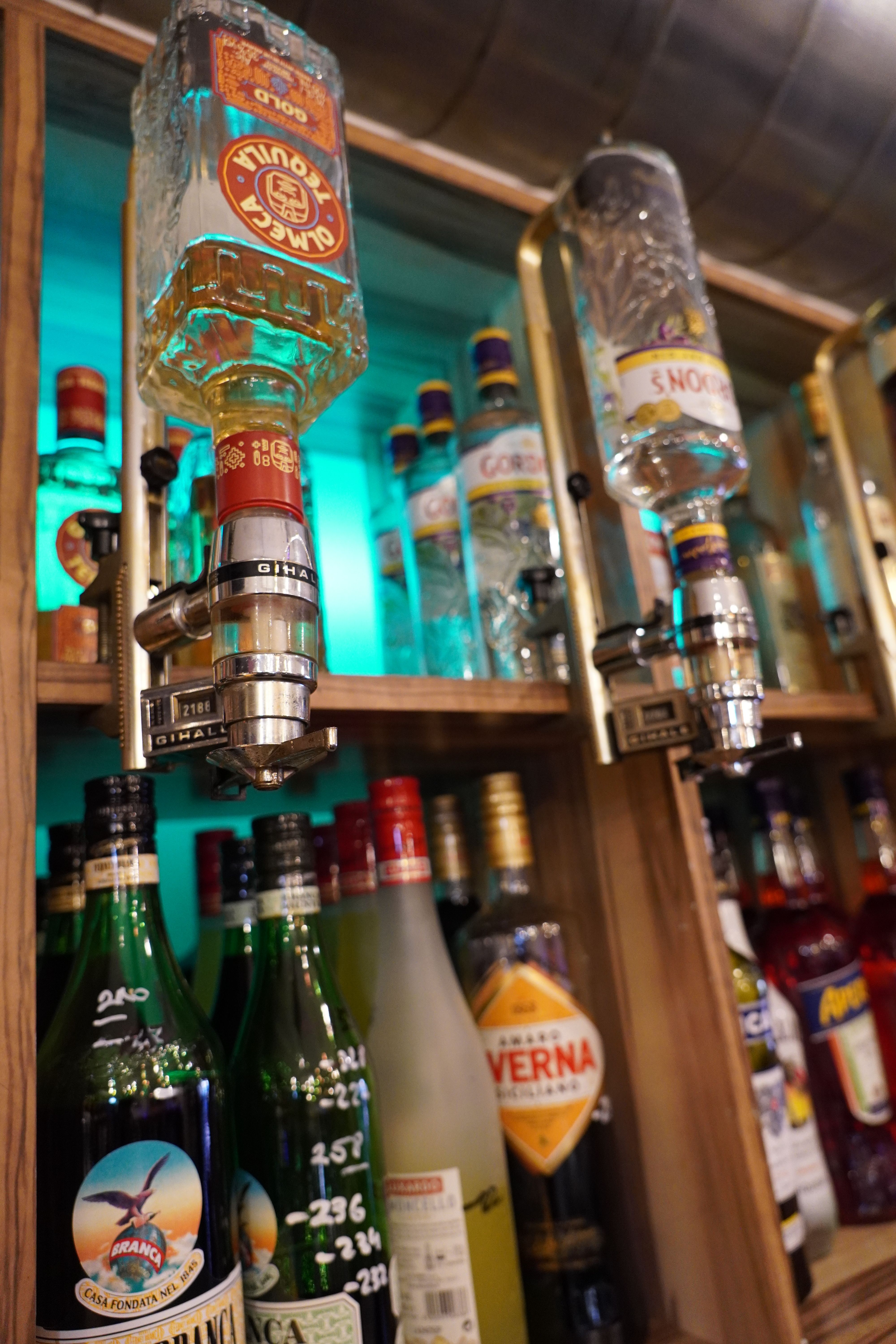 Close-up of bottles of spirits in a bar with taps.