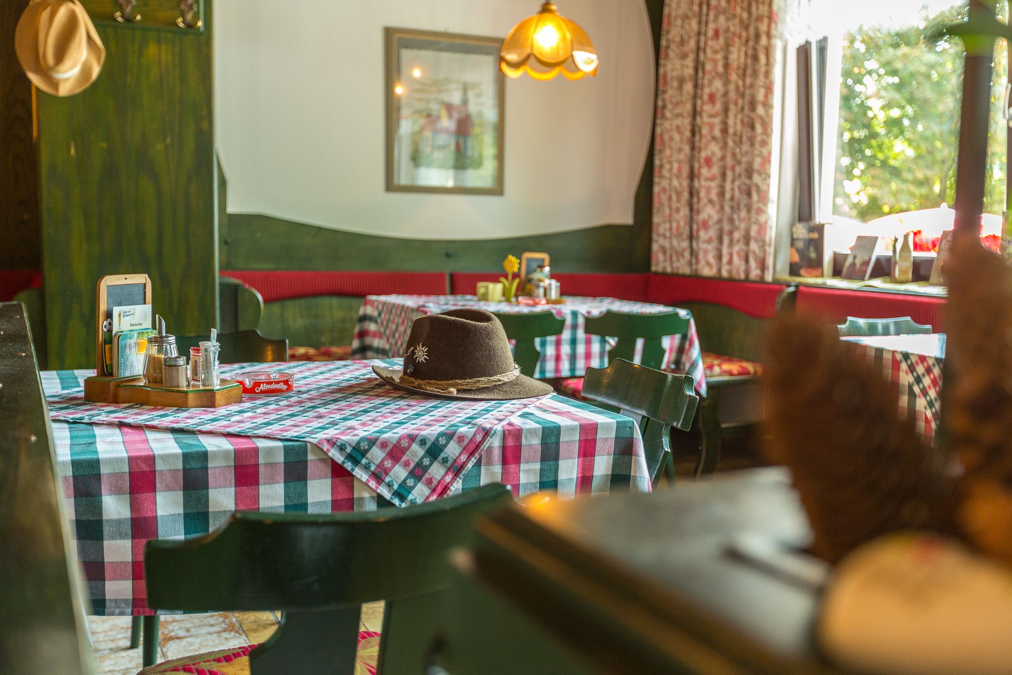 Cozy dining room with checkered tablecloths and a hat on the table.