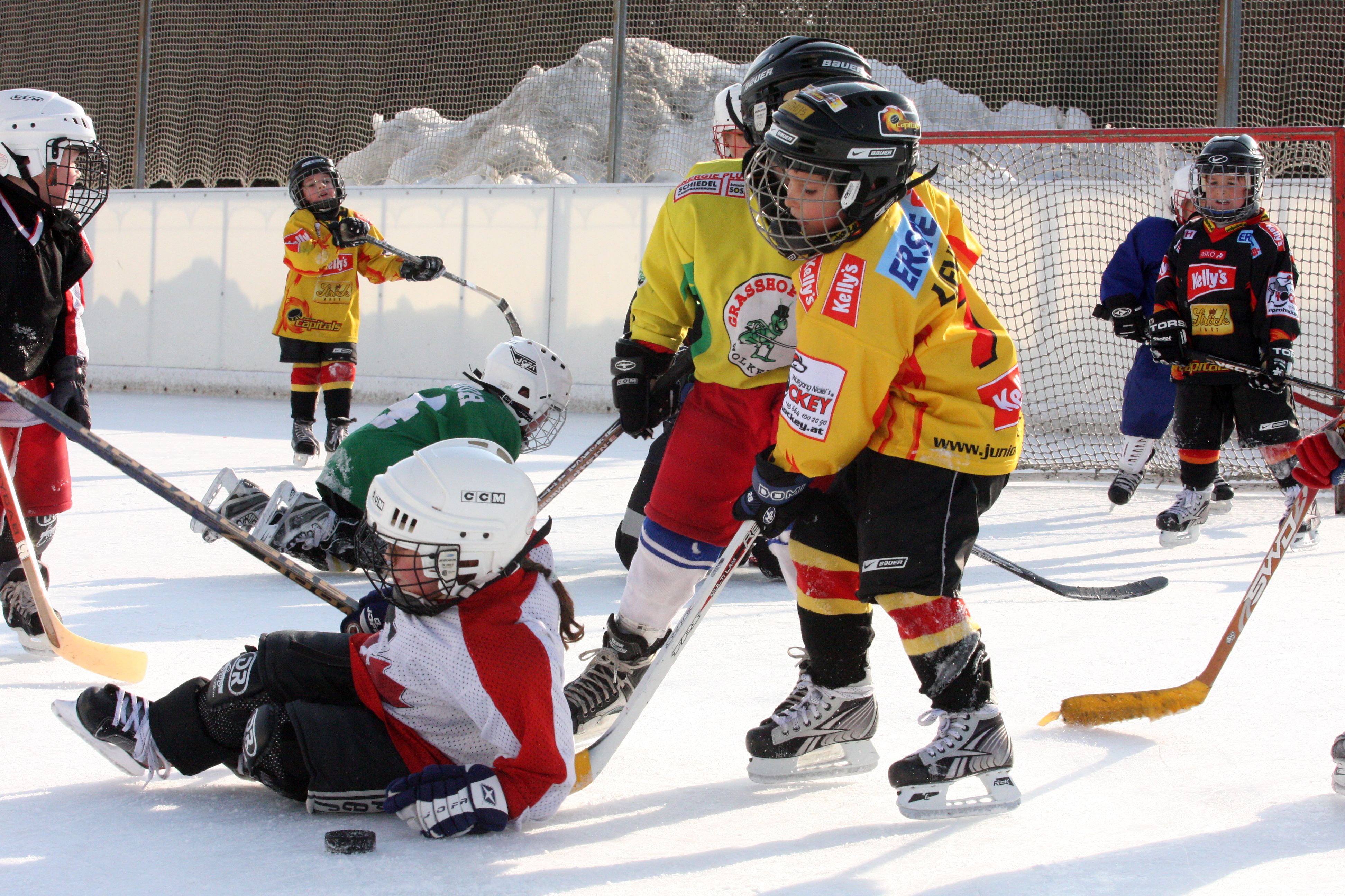 Children playing ice hockey on an outdoor rink.