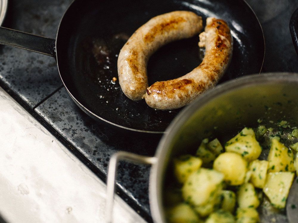 Sausage in a pan with potatoes in a pot.